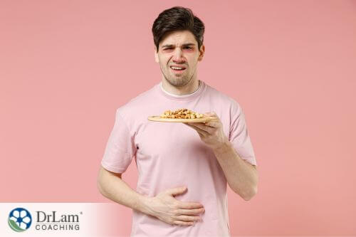 An image of a man holding his stomach with one hand and food on the other